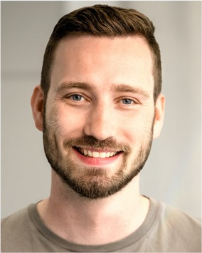 Maik Hummel, head and shoulders, monochrome: short dark hair, a full beard, looking at the camera.